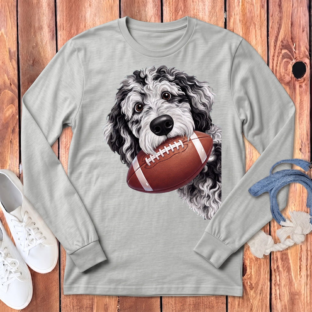 A light gray long-sleeve shirt featuring a graphic of a black and white doodle dog holding a football.