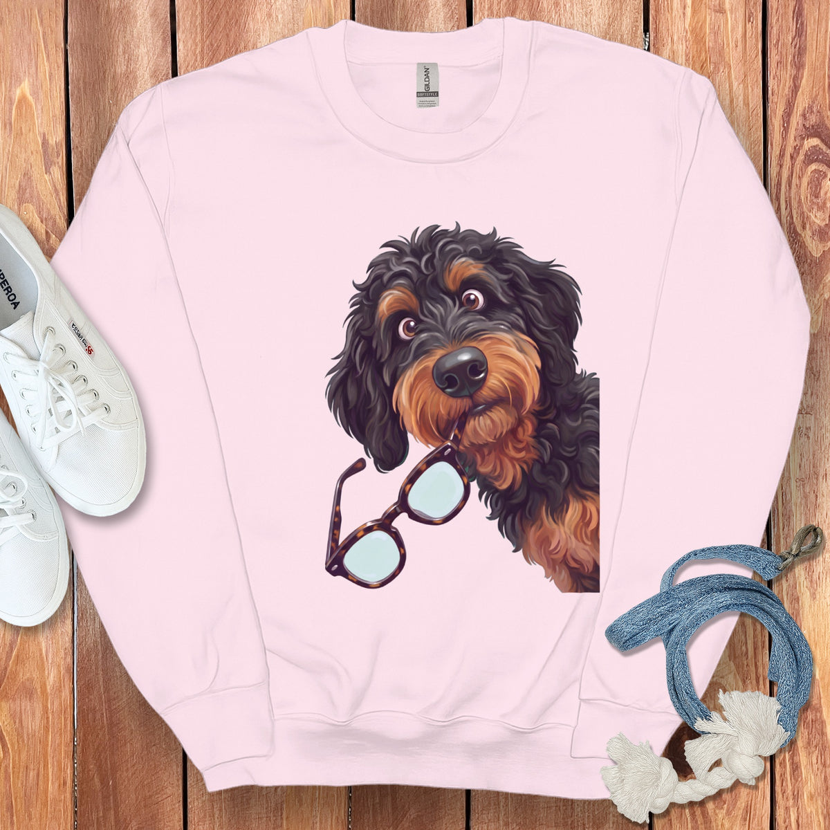 Light pink crewneck sweatshirt featuring a graphic of a dark curly-haired dog holding glasses.