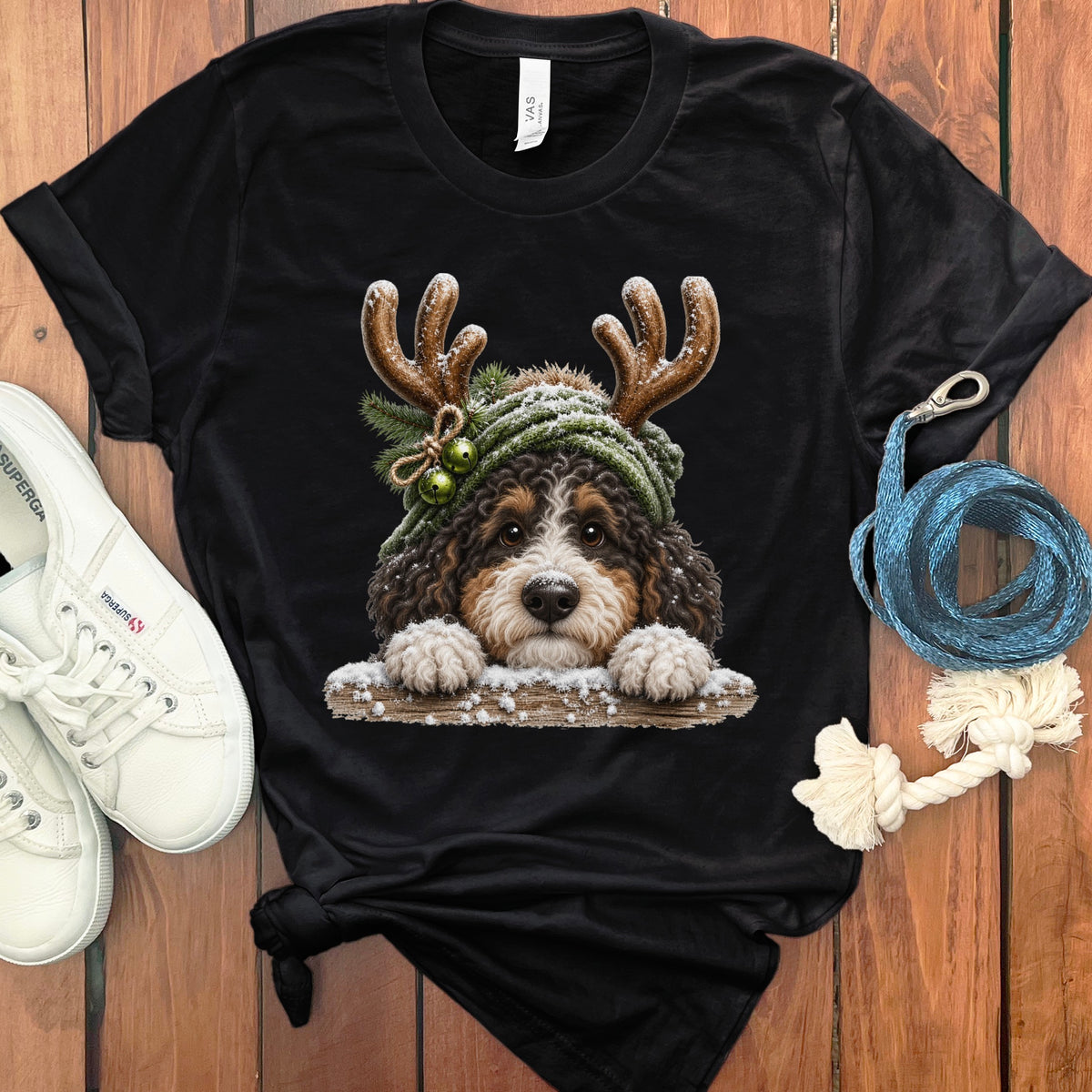 Black t-shirt featuring a fluffy Bernese Mountain Dog wearing reindeer antlers and a green beanie.