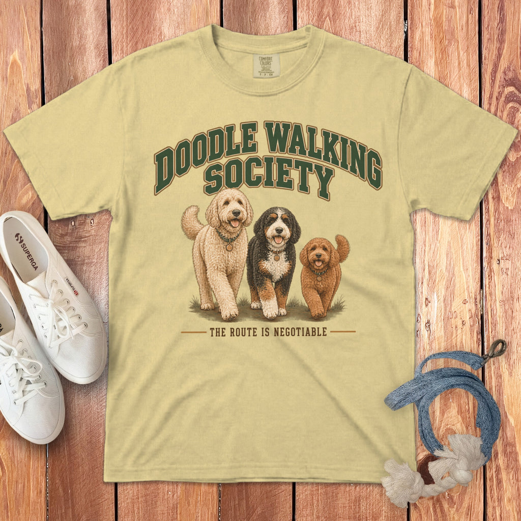A light yellow t-shirt features a vintage graphic of three doodles and text reading Doodle Walking Society.