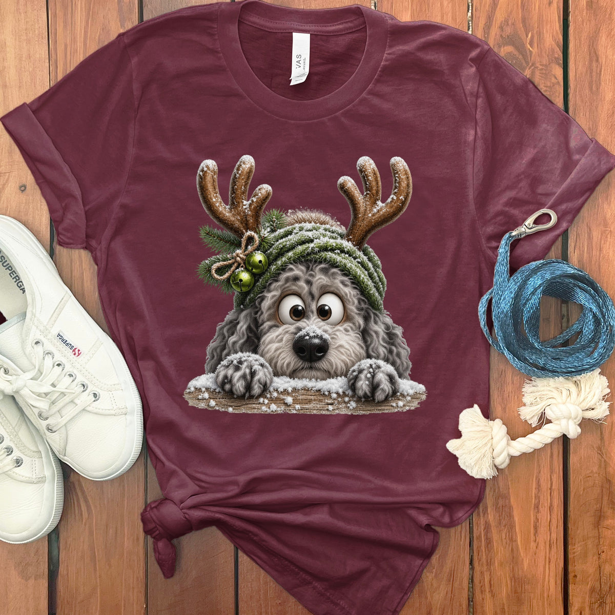 Maroon t-shirt with fluffy dog wearing antlers and a green hat with bells.