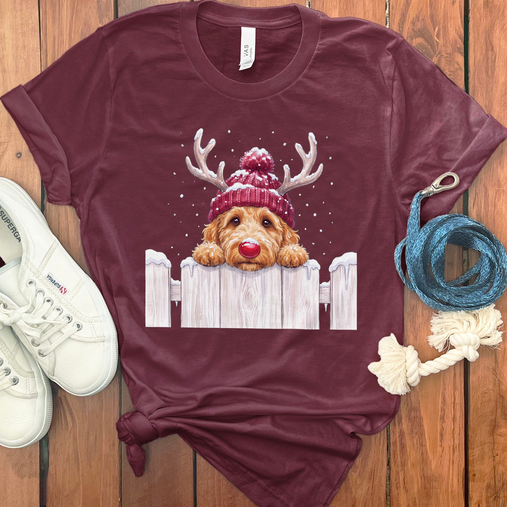 Maroon t-shirt with a watercolor dog wearing a Santa hat and antlers over a fence.