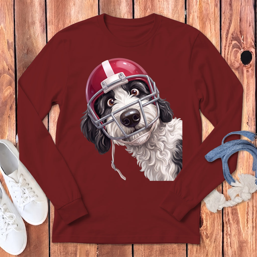 Black and white dog wearing a red and white football helmet on a maroon long-sleeve shirt.