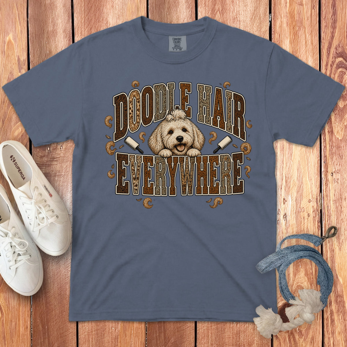 Slate blue t-shirt featuring a goldoodle graphic and the text Doodle Hair Everywhere on a wooden background.