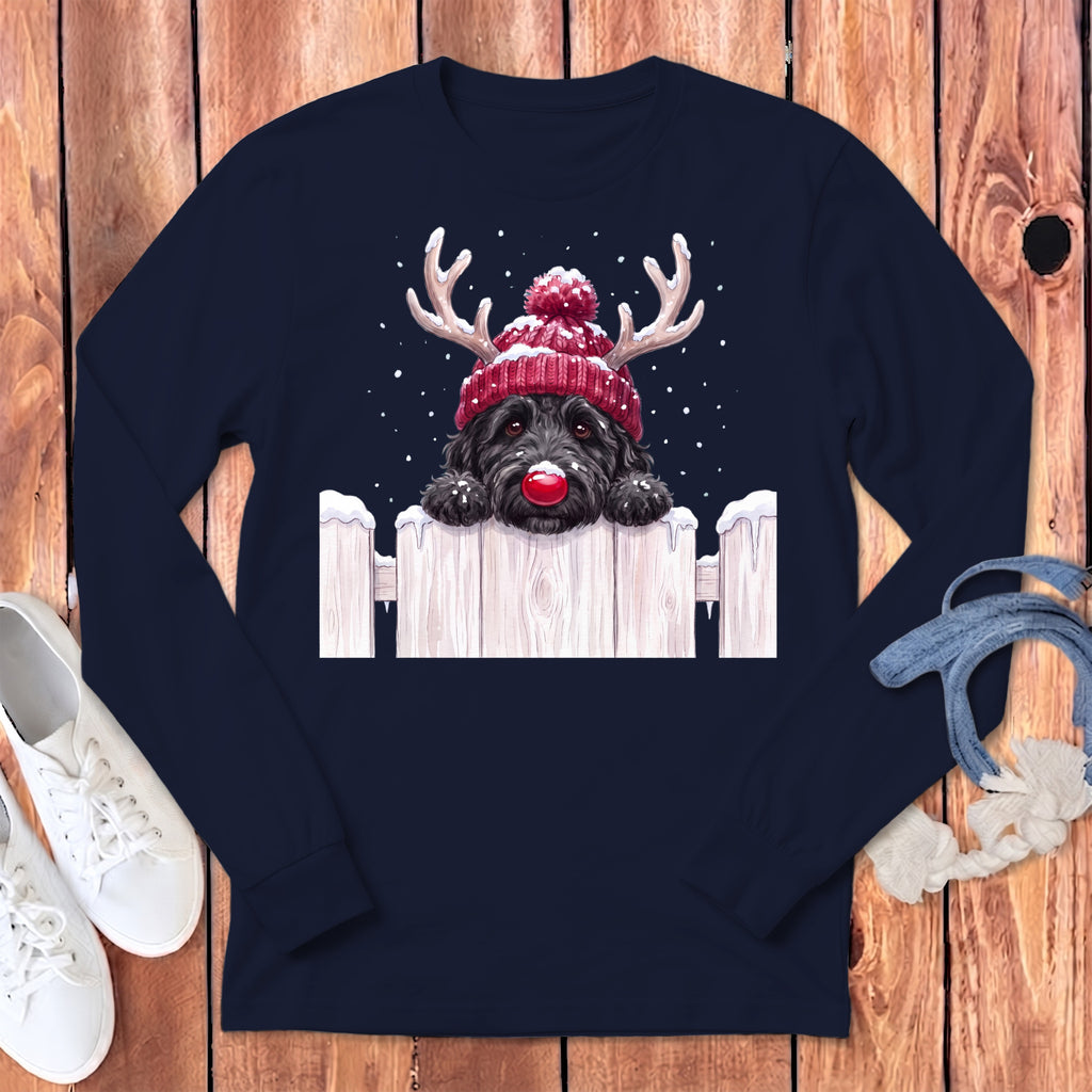 Black dog with reindeer antlers and red nose peeking over a snowy fence.