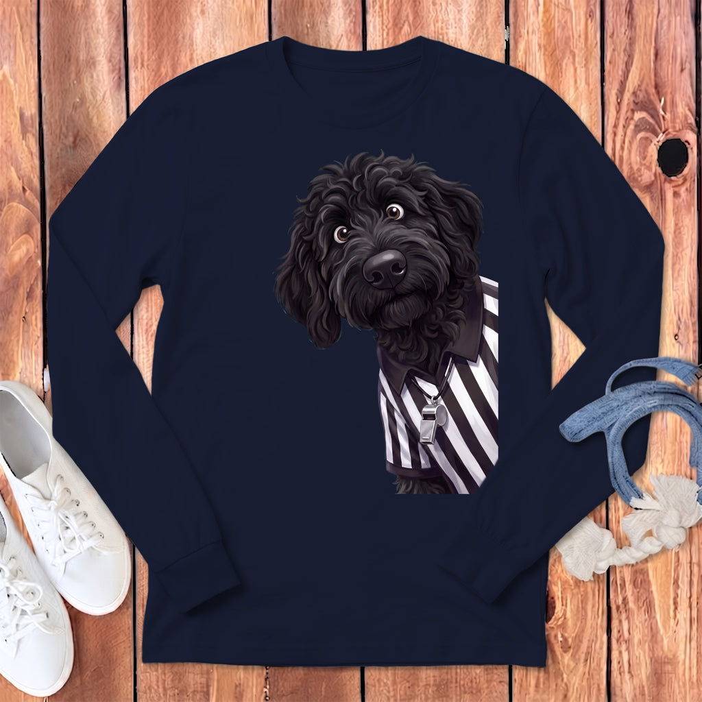 Black doodle dog wearing a referee shirt with a whistle on a navy long-sleeve shirt.