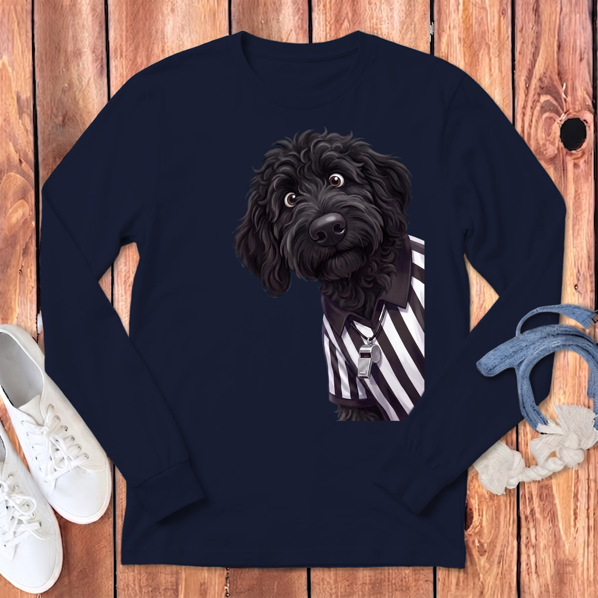 Black doodle dog wearing a referee shirt with a whistle on a navy long-sleeve shirt.