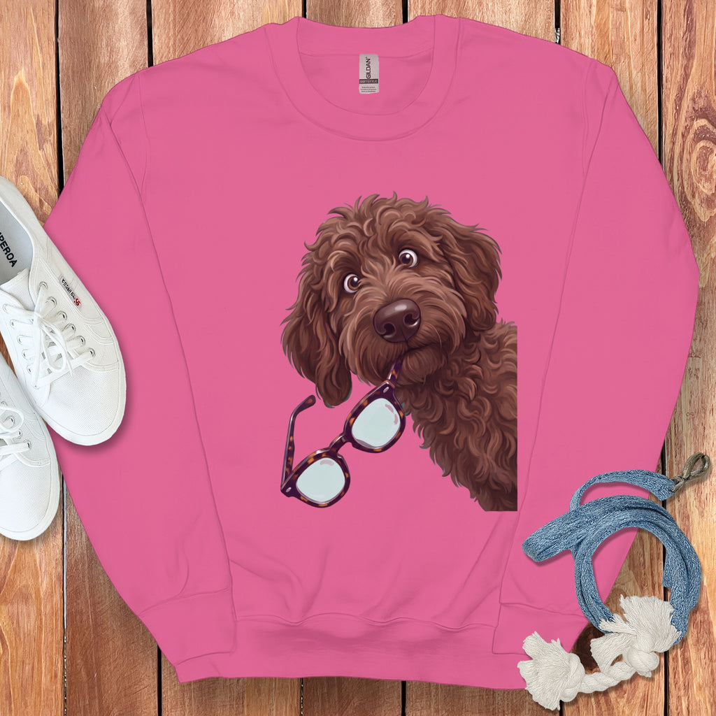 A pink sweatshirt featuring an illustration of a brown curly dog holding glasses in its mouth.
