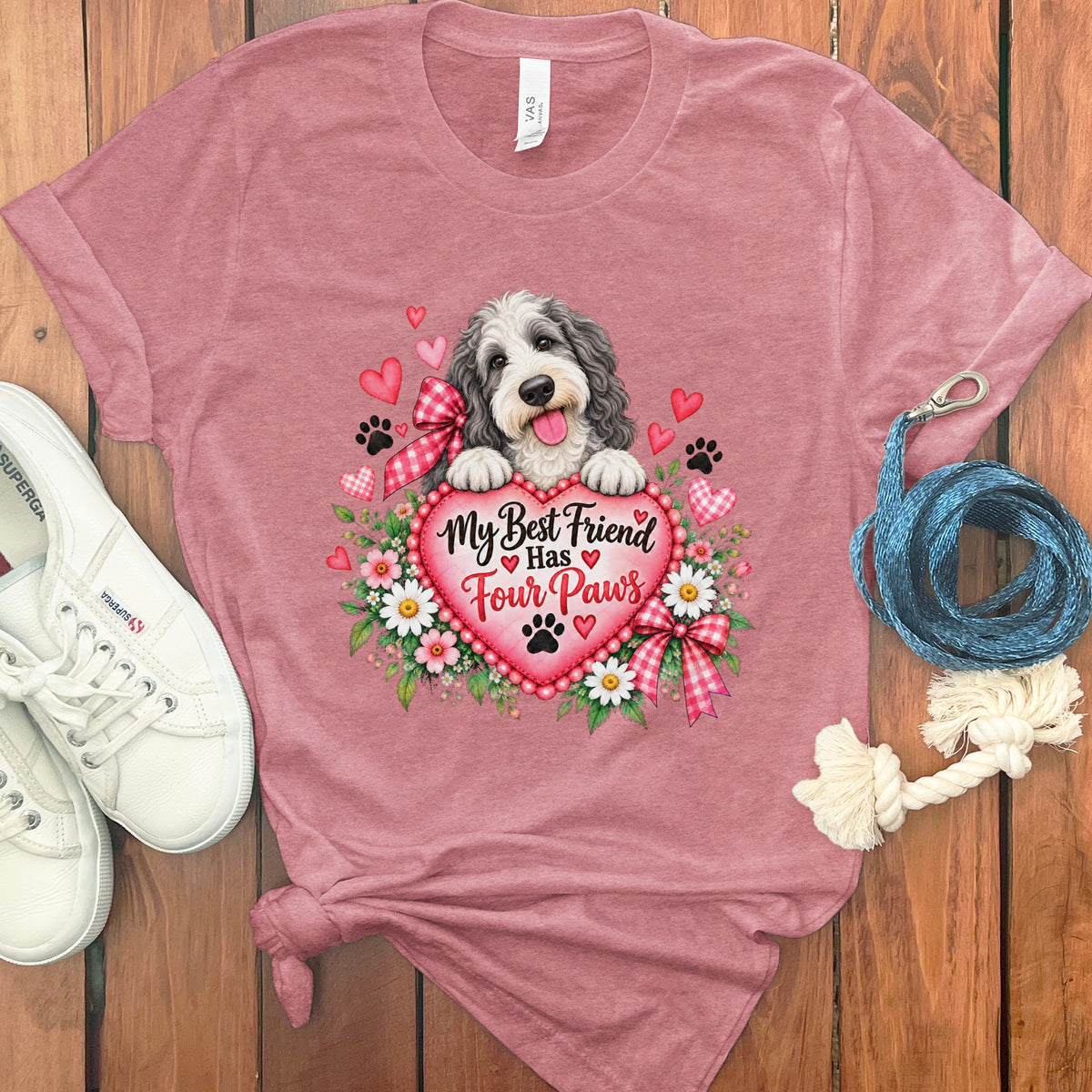 Dusty pink t-shirt featuring a doodle dog graphic, a heart that reads My Best Friend Has Four Paws, flowers, and paw prints.