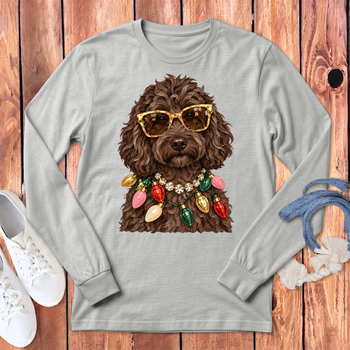 Brown dog wearing sunglasses and a colorful Christmas lights necklace on a gray shirt.