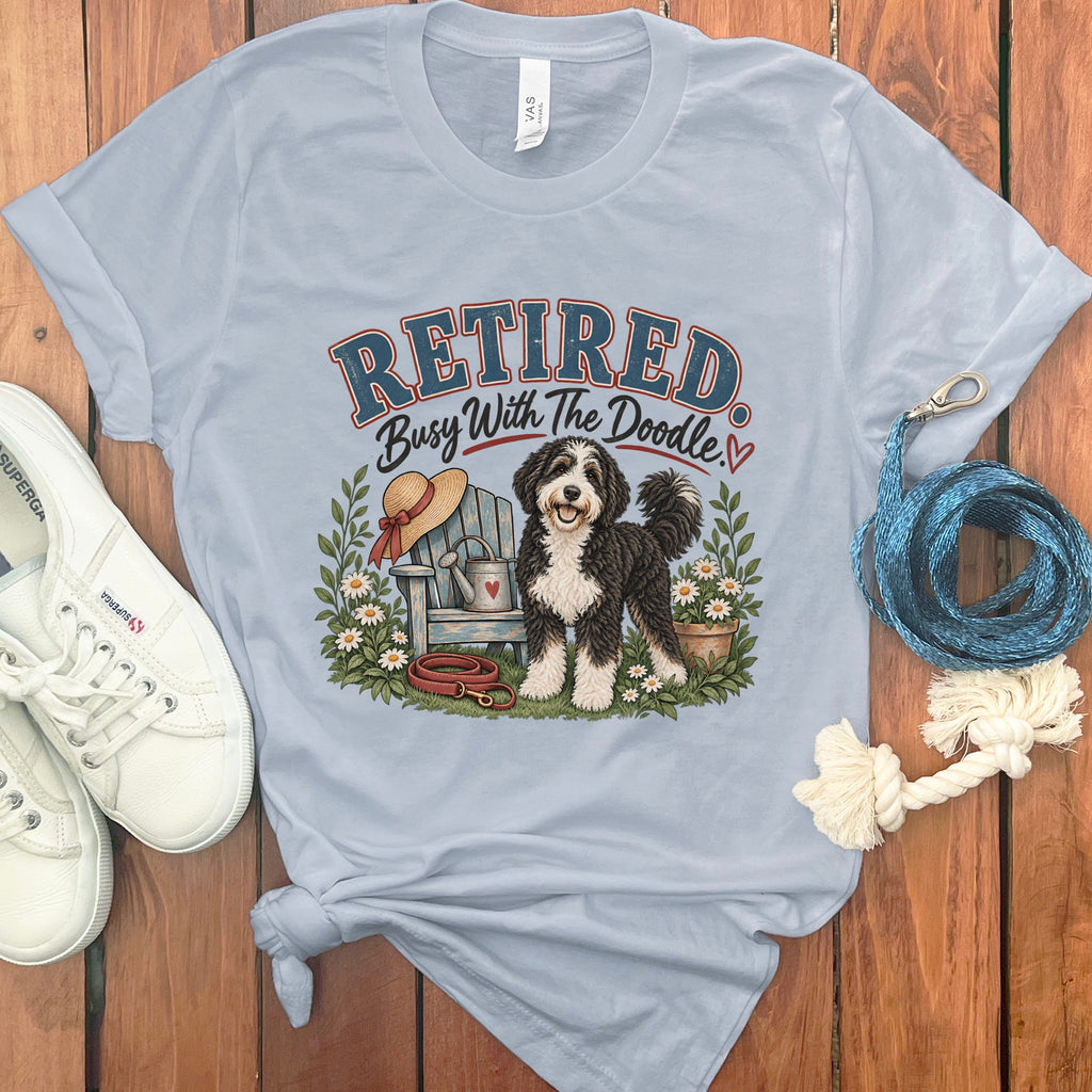 Light blue t-shirt with graphic text "Retired Busy With The Doodle" and a doodle dog.