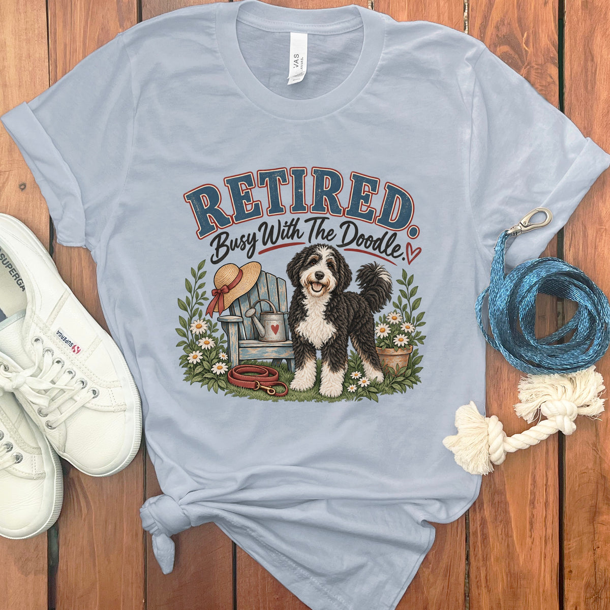 Light blue t-shirt with graphic text "Retired Busy With The Doodle" and a doodle dog.