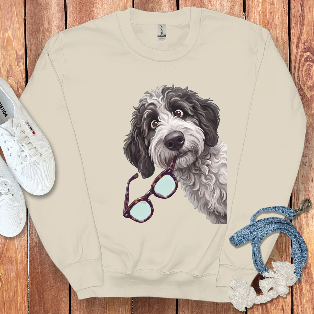 Beige crewneck sweatshirt featuring a graphic of a fluffy black and white dog biting glasses.