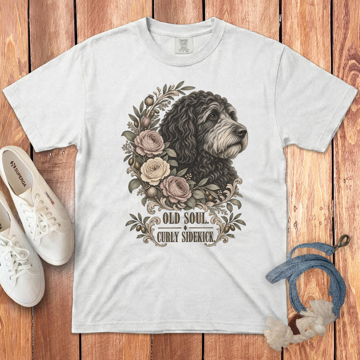 White t-shirt featuring a graphic of a curly-haired dog surrounded by roses and text reading OLD SOUL CURLY SIDEKICK.