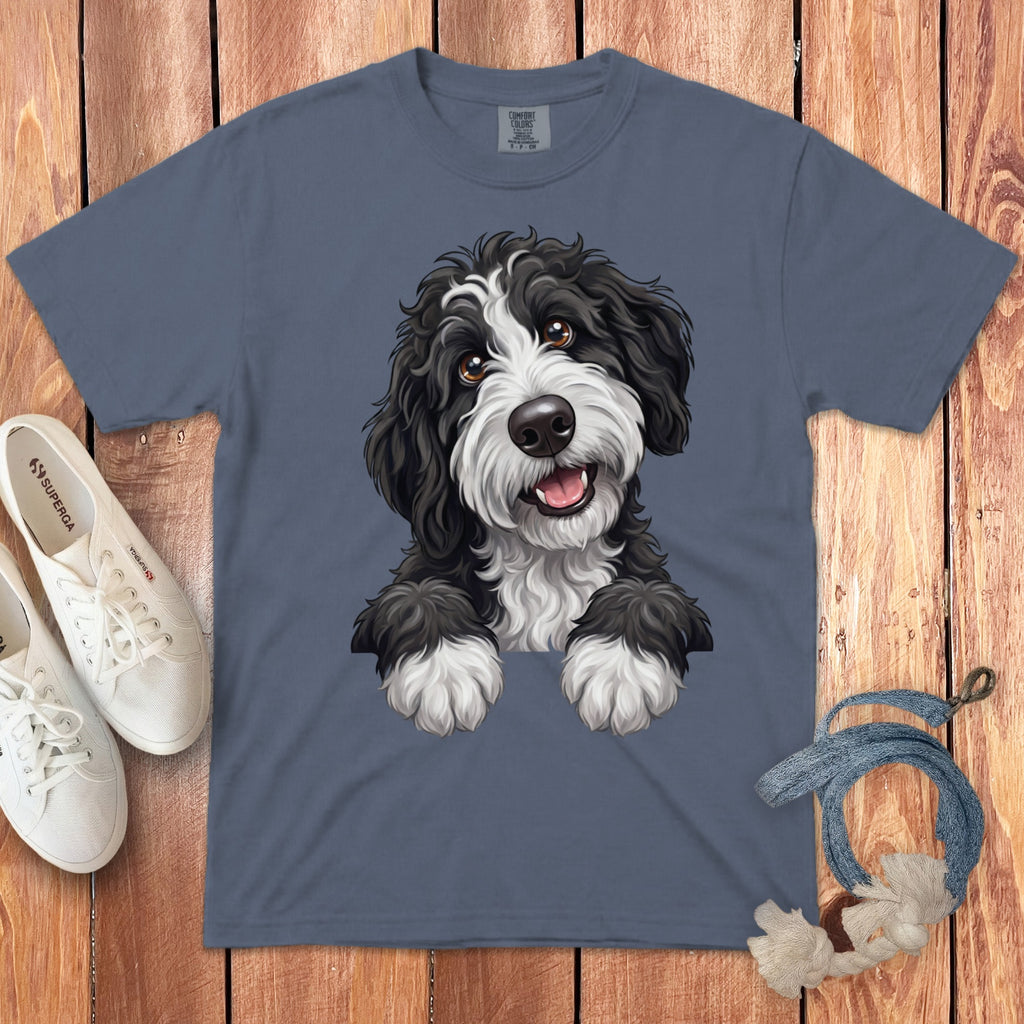 Blue t-shirt with a drawing of a black and white fluffy dog's head and paws.