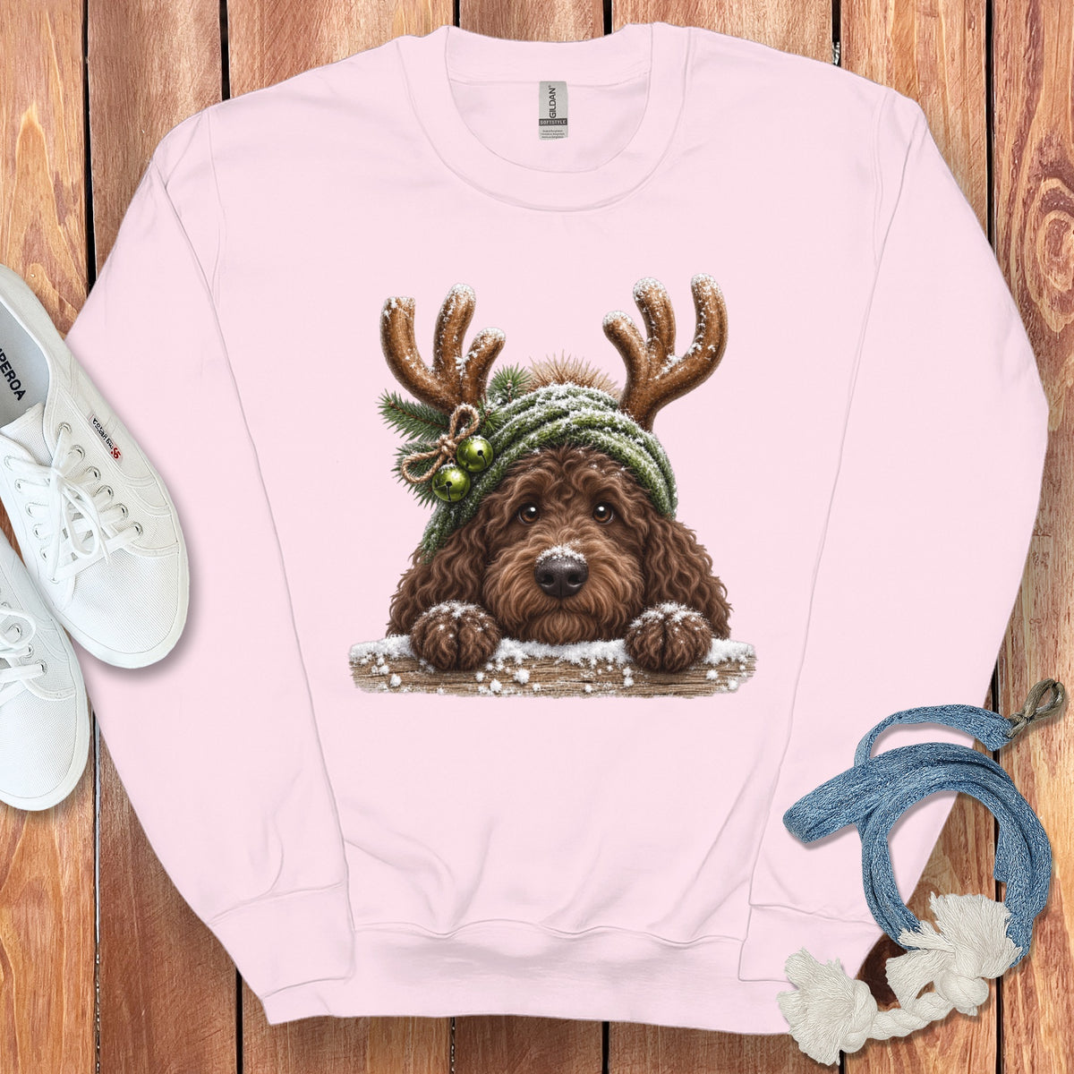 Pink sweatshirt with a brown dog wearing reindeer antlers and a green hat.