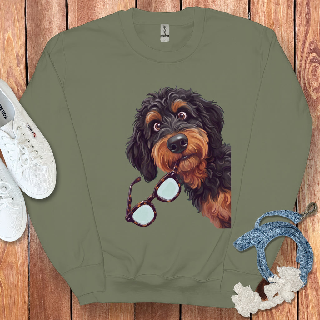 An olive green crewneck sweatshirt featuring an illustrated black and brown dog holding glasses in its mouth.