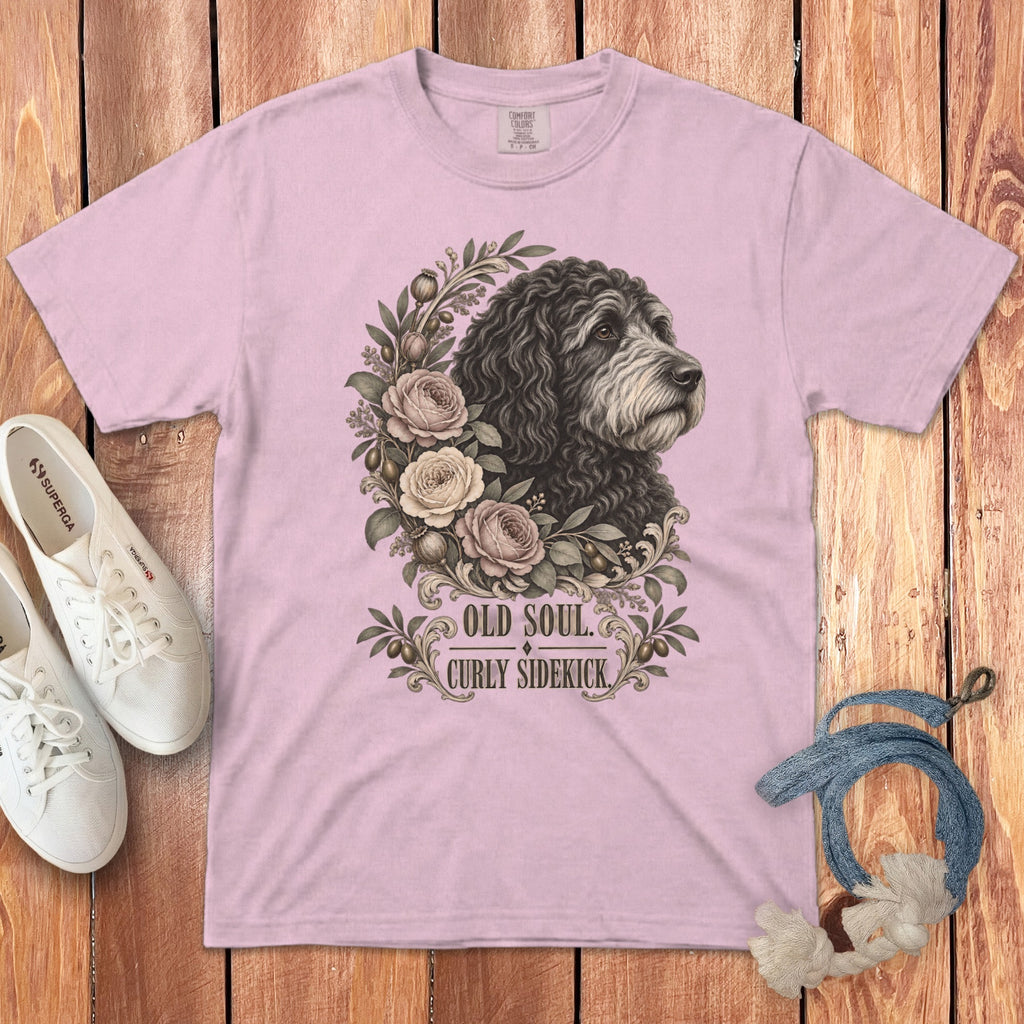 A light pink t-shirt featuring a graphic of a curly dog, roses, and the text Old Soul Curly Sidekick.