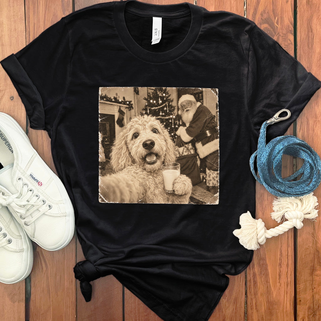A black t-shirt features a vintage-style graphic of a fluffy dog holding a glass of milk with Santa Claus in the background.