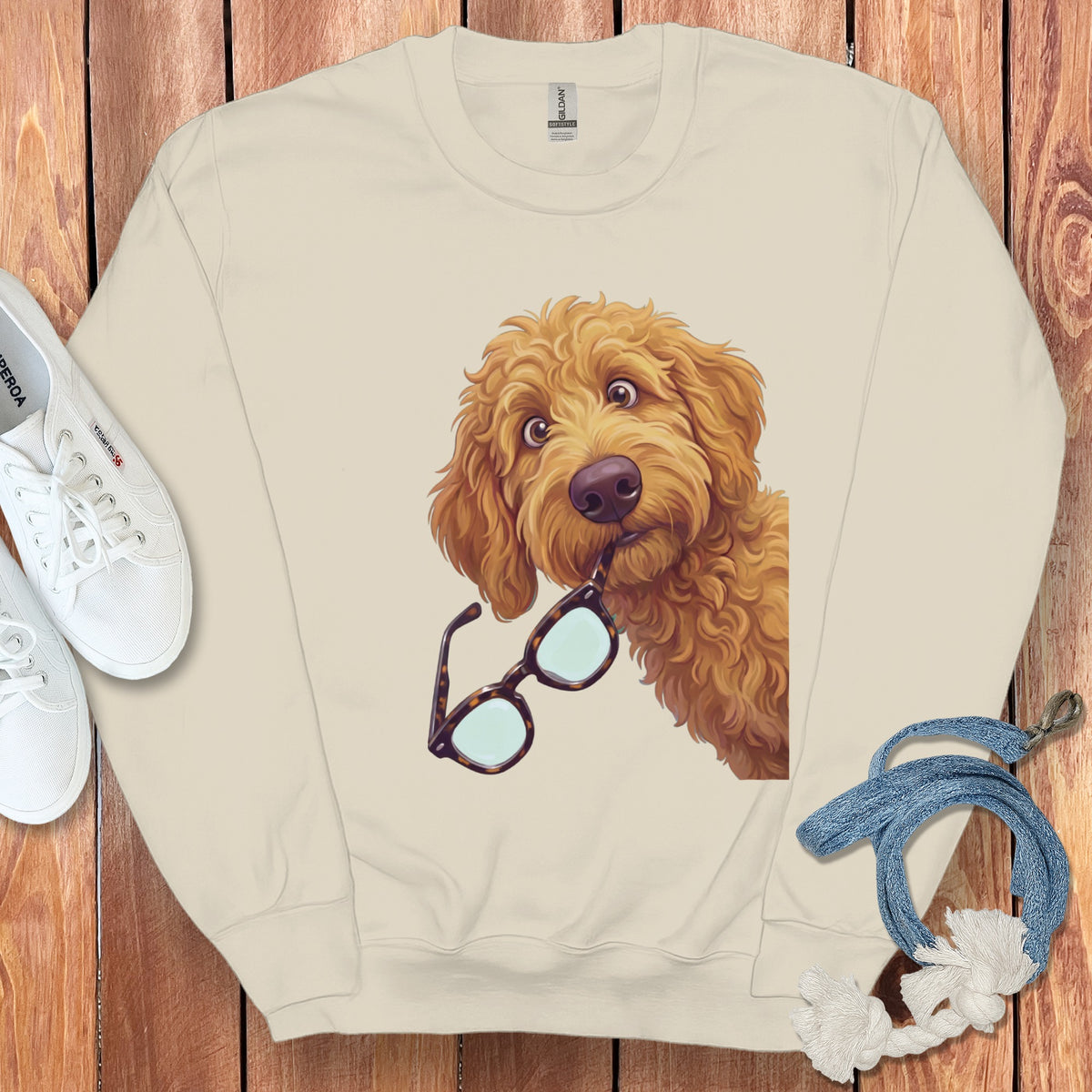 Cream-colored crewneck sweatshirt featuring an illustration of a fluffy golden dog holding glasses in its mouth.
