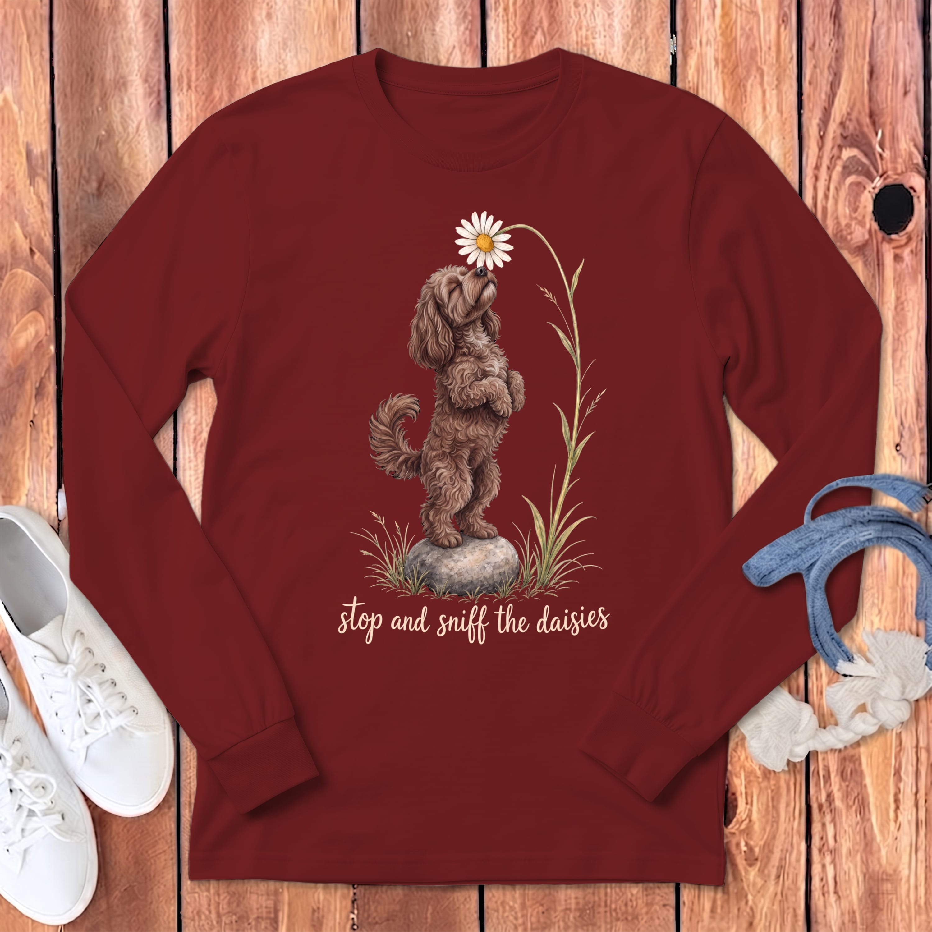 Maroon long-sleeve shirt with a brown dog sniffing a daisy, text "stop and sniff the daisies."