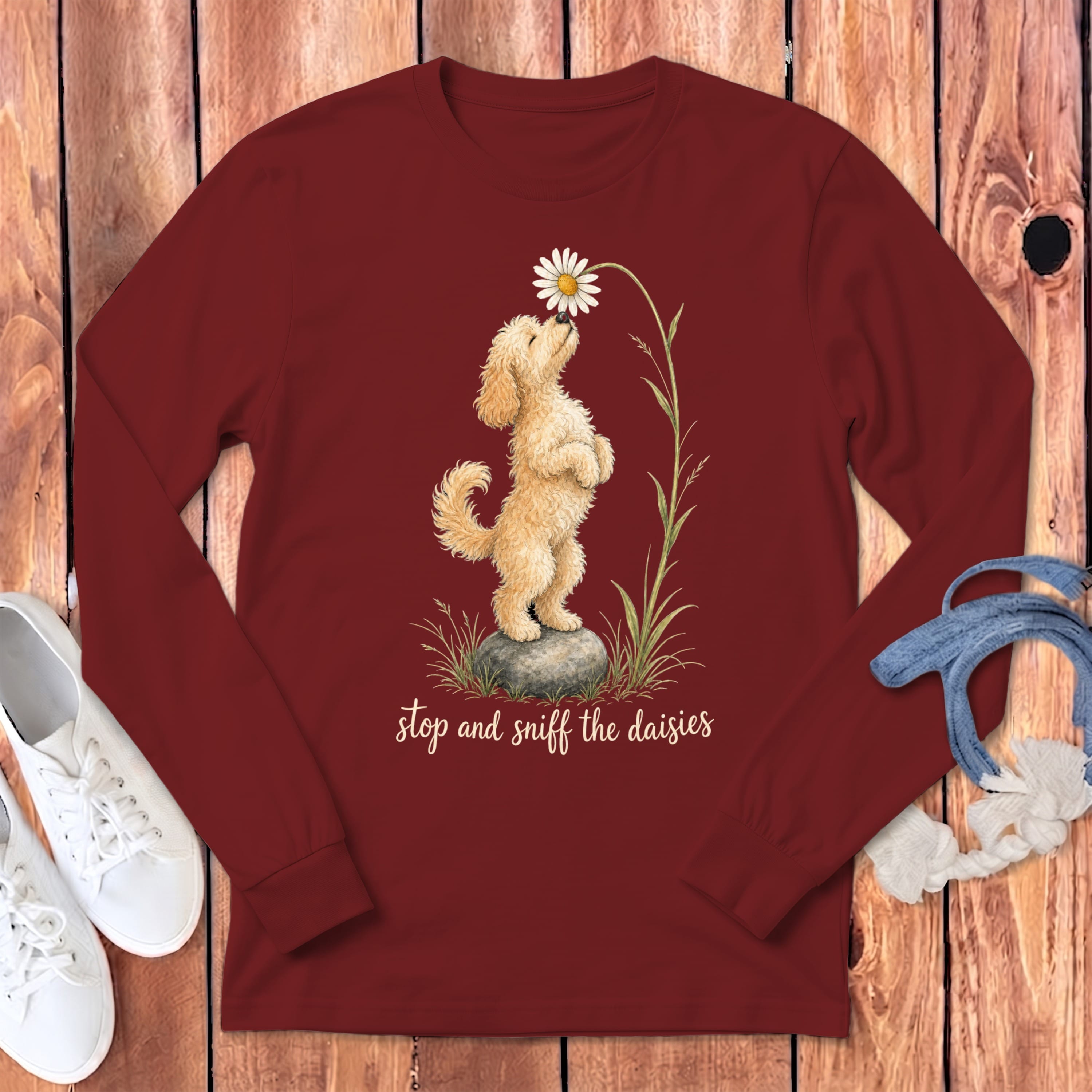 Maroon long-sleeve shirt with a fluffy dog sniffing a daisy and text "stop and sniff the daisies."