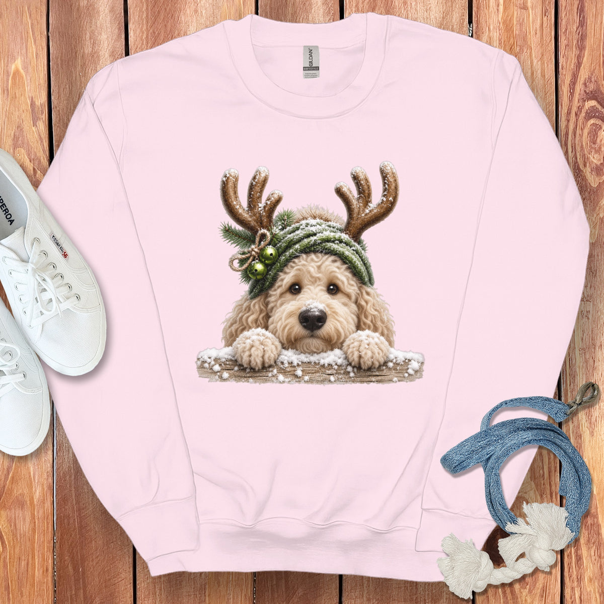 Pink sweatshirt with a fluffy dog wearing reindeer antlers and a green hat.