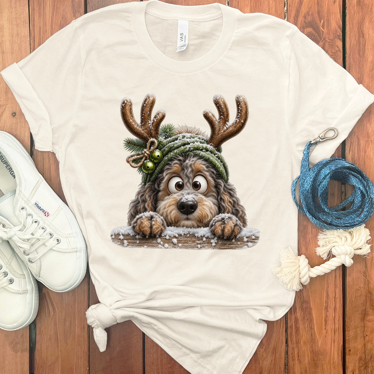 Cream t-shirt with a Christmas dog illustration wearing antlers and a green hat.