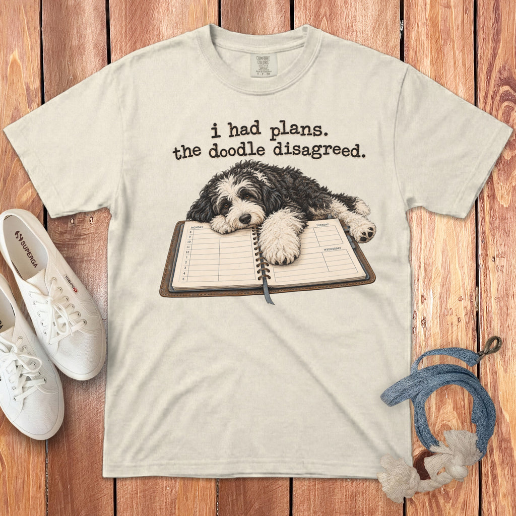 Cream crewneck t-shirt featuring a doodle dog resting on a planner with text reading I had plans. the doodle disagreed.