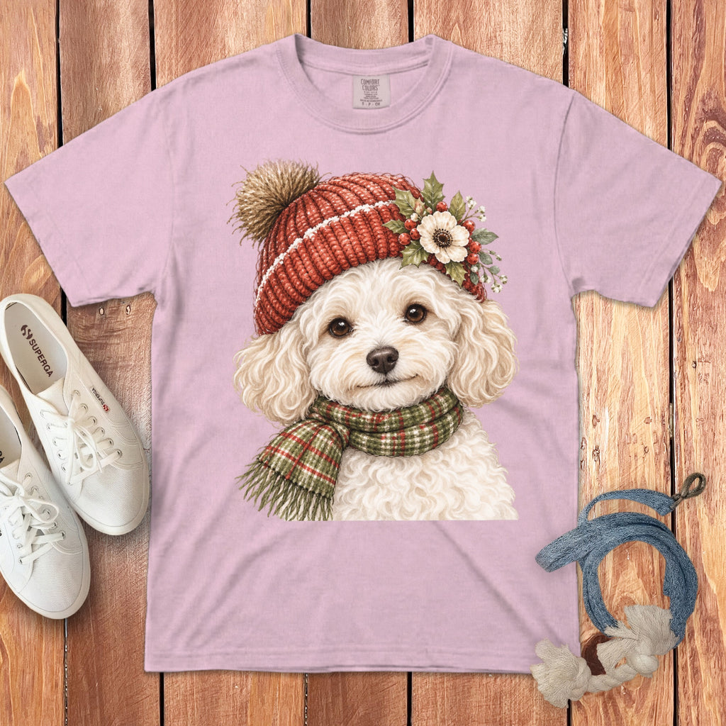 Pink t-shirt featuring a watercolor poodle wearing a red knit hat and green plaid scarf.