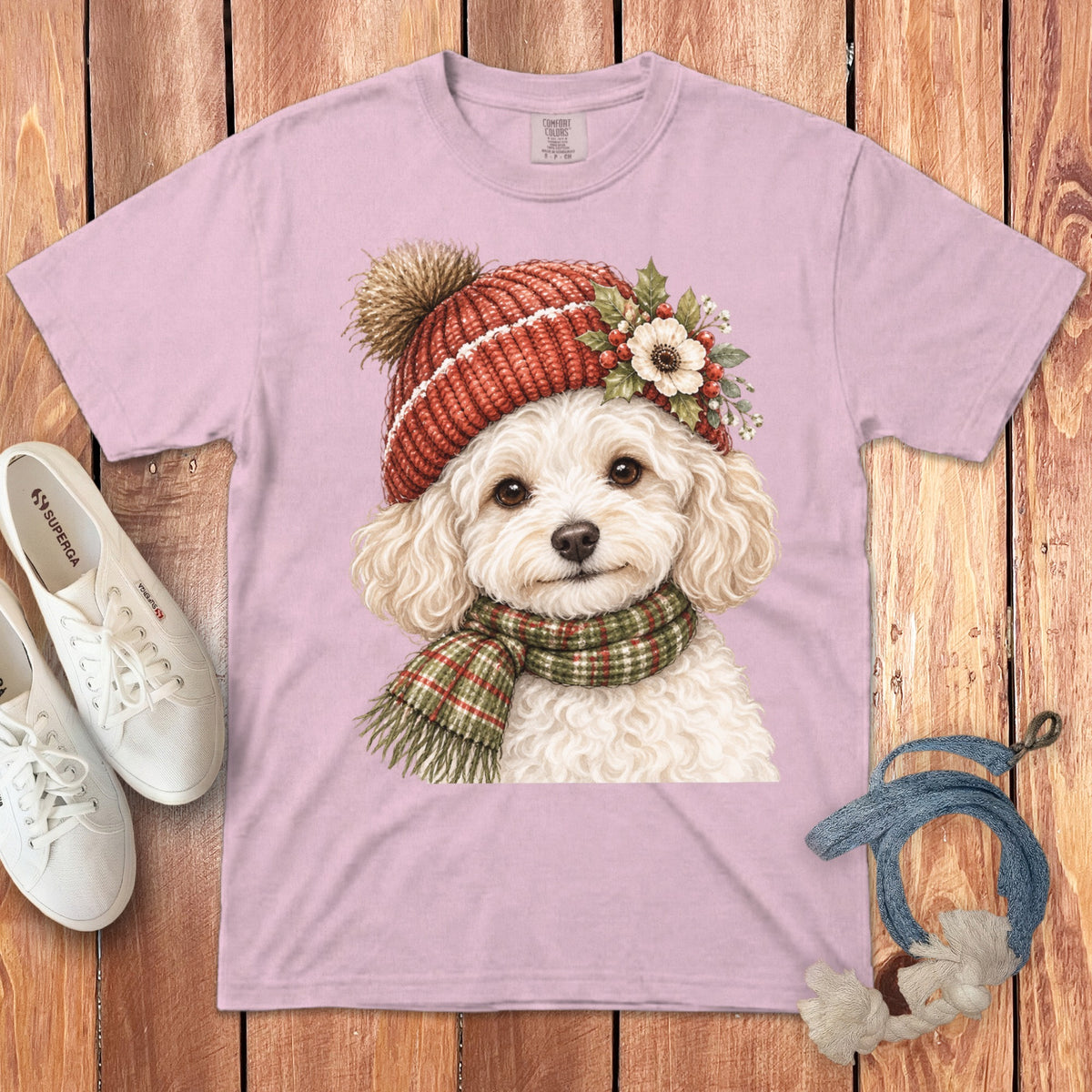 Pink t-shirt featuring a watercolor poodle wearing a red knit hat and green plaid scarf.