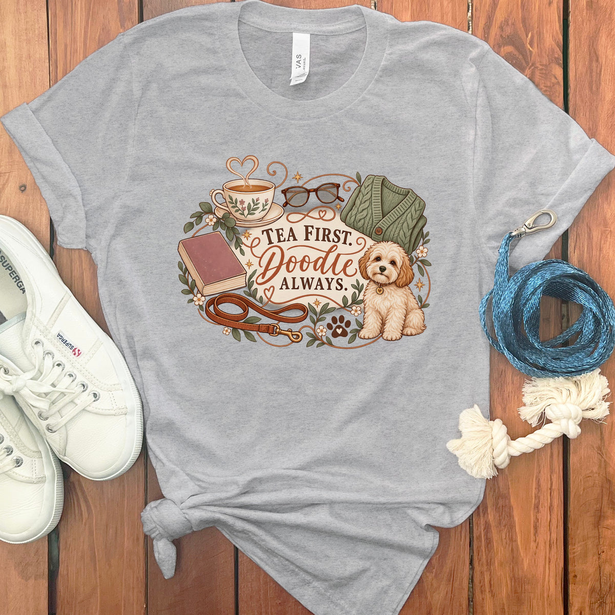 Gray t-shirt with a Doodle dog, tea, book, leash, and sweater graphic that reads "Tea First. Doodle Always."