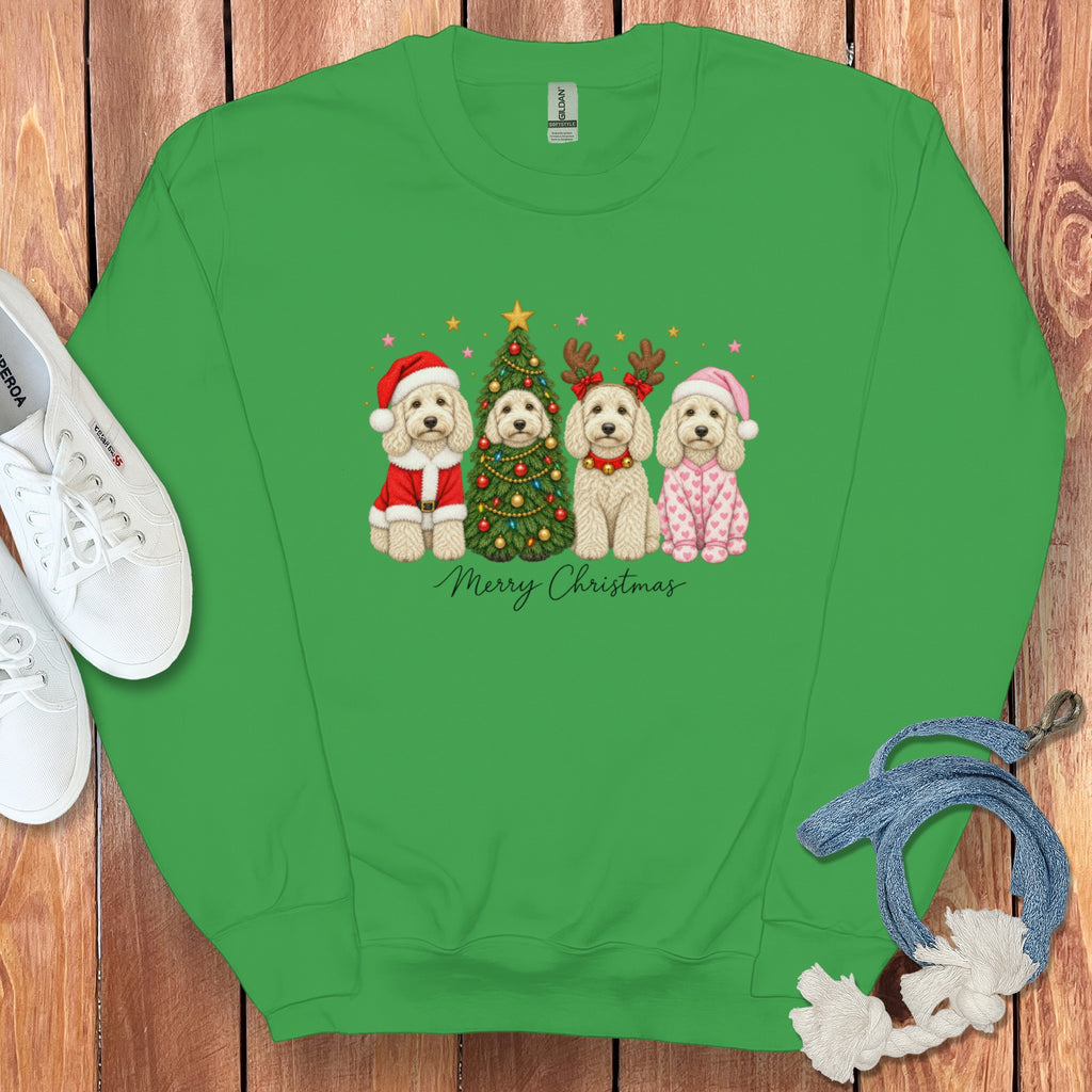 Green crewneck sweatshirt featuring a graphic of four doodle dogs celebrating Christmas alongside white sneakers and a blue rope toy on a wooden background.