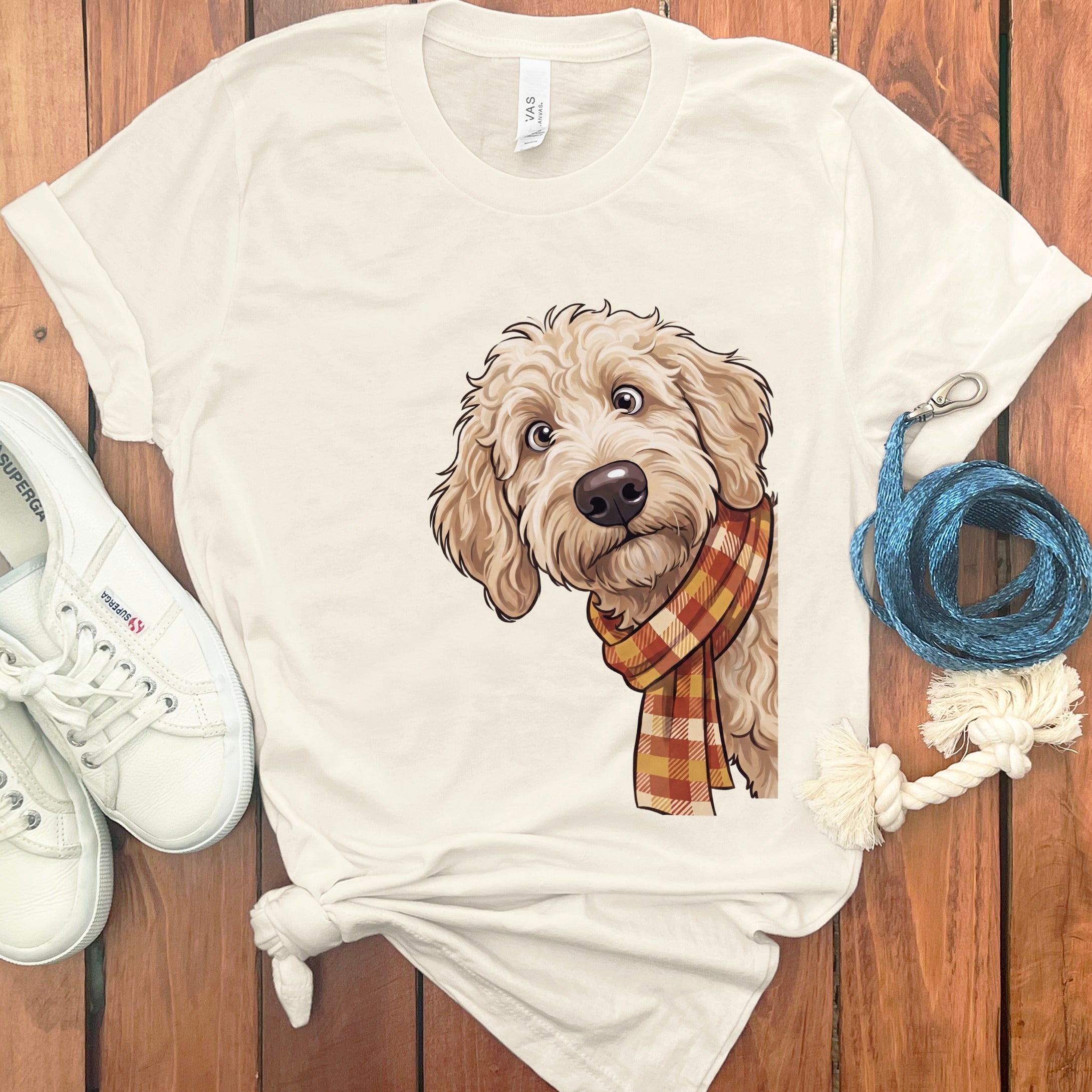 Cream t-shirt with illustration of a fluffy dog wearing a plaid scarf.
