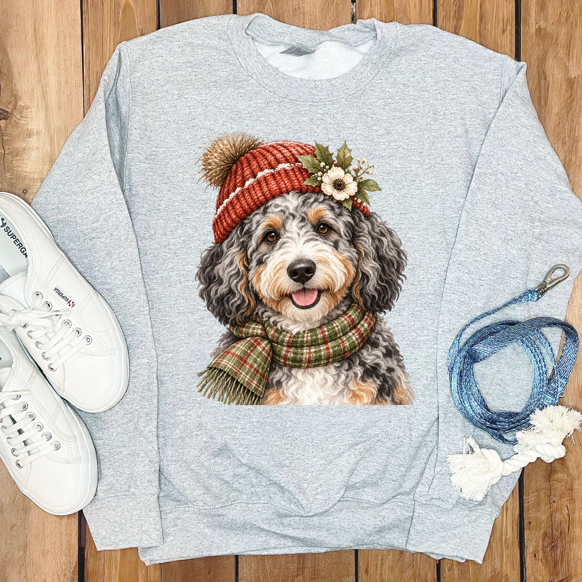 Light gray sweatshirt with a Bernedoodle wearing a knitted hat and scarf.