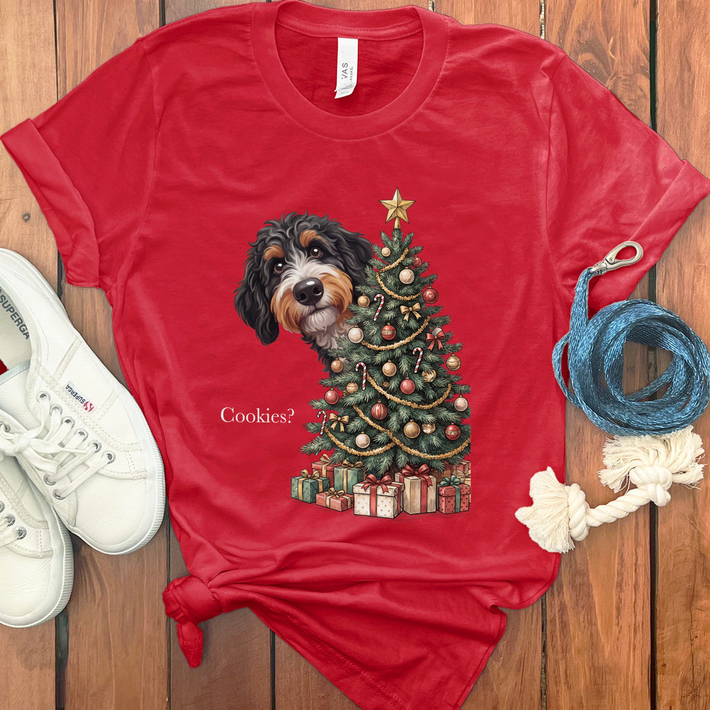 Bernese Mountain Dog peeking by Christmas tree with gifts and text "Cookies?".