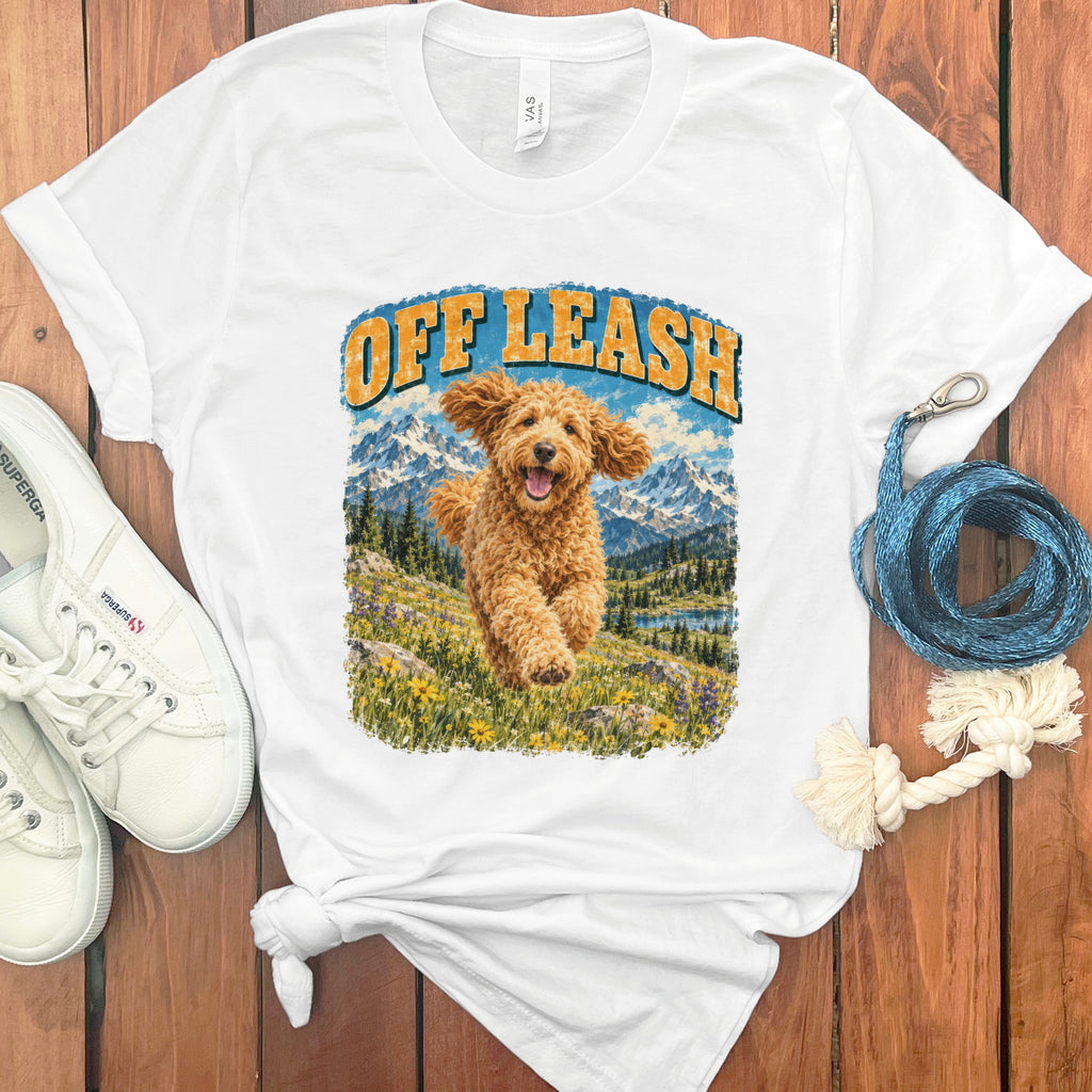White t-shirt with "Off Leash" text and running golden doodle in mountain landscape.