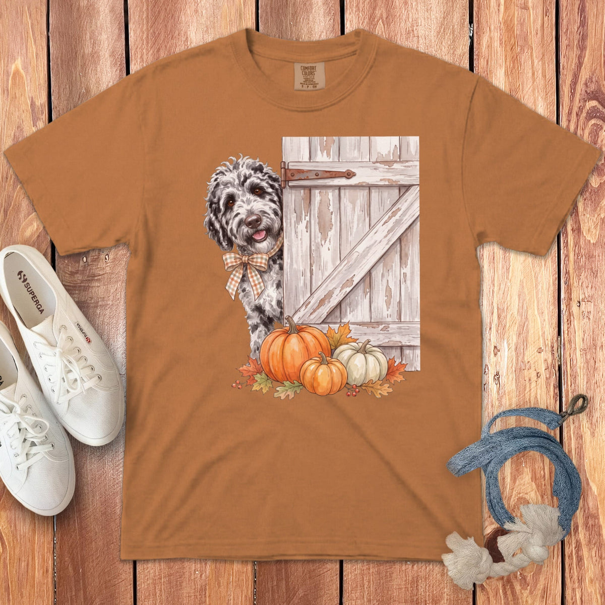 Brown t-shirt with a dog peeking from behind a rustic door with pumpkins.