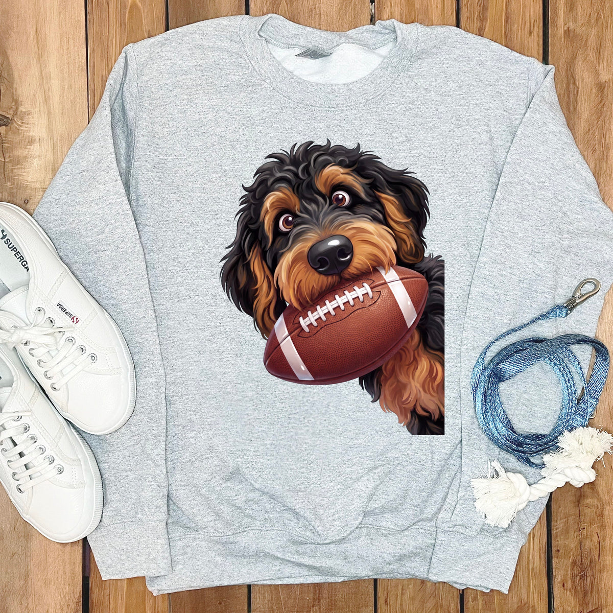 Gray sweatshirt with a doodle dog graphic holding a football.