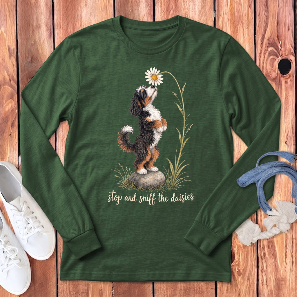 Bernese Mountain Dog smelling a daisy with text "stop and sniff the daisies".