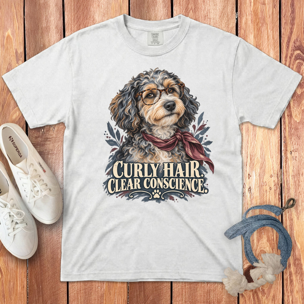 A white t-shirt featuring a graphic of a curly-haired dog wearing glasses and a scarf, with the text Curly Hair Clear Conscience.