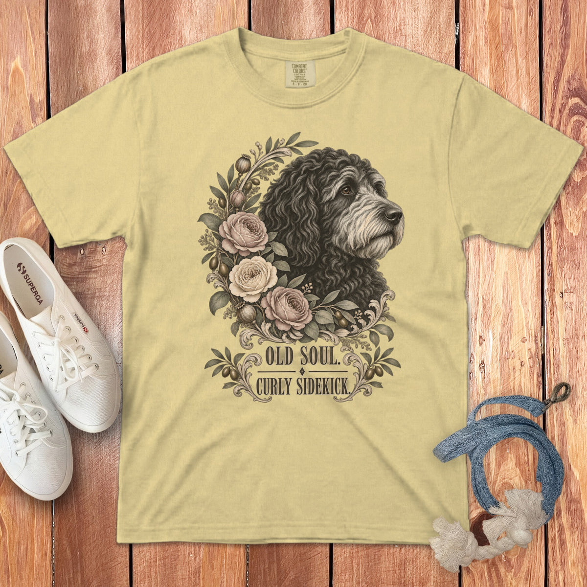 Pale yellow t-shirt featuring a black dog graphic, floral wreath, and text reading OLD SOUL CURLY SIDEKICK.