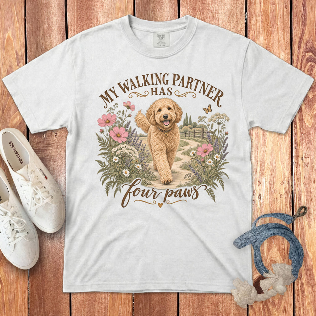 A white t-shirt featuring a goldendoodle graphic and the text My walking partner has four paws.