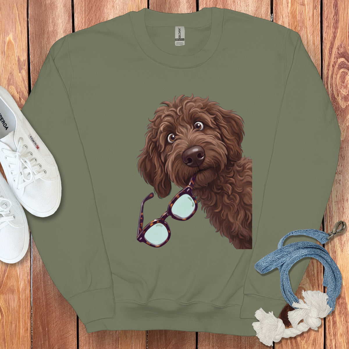 An olive green crewneck sweatshirt featuring a graphic of a brown doodle dog biting glasses.