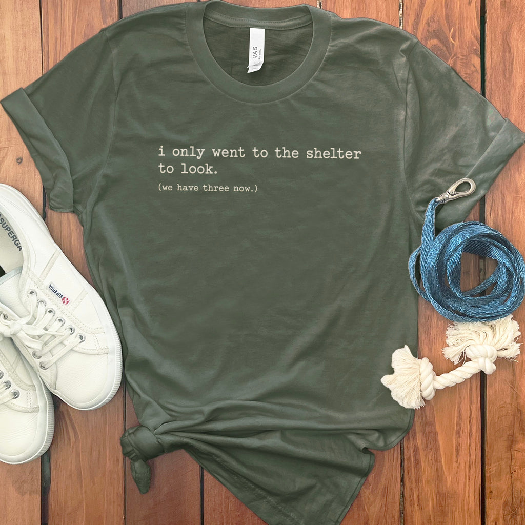 Olive green t-shirt with white text: "i only went to the shelter to look. (we have three now.)"