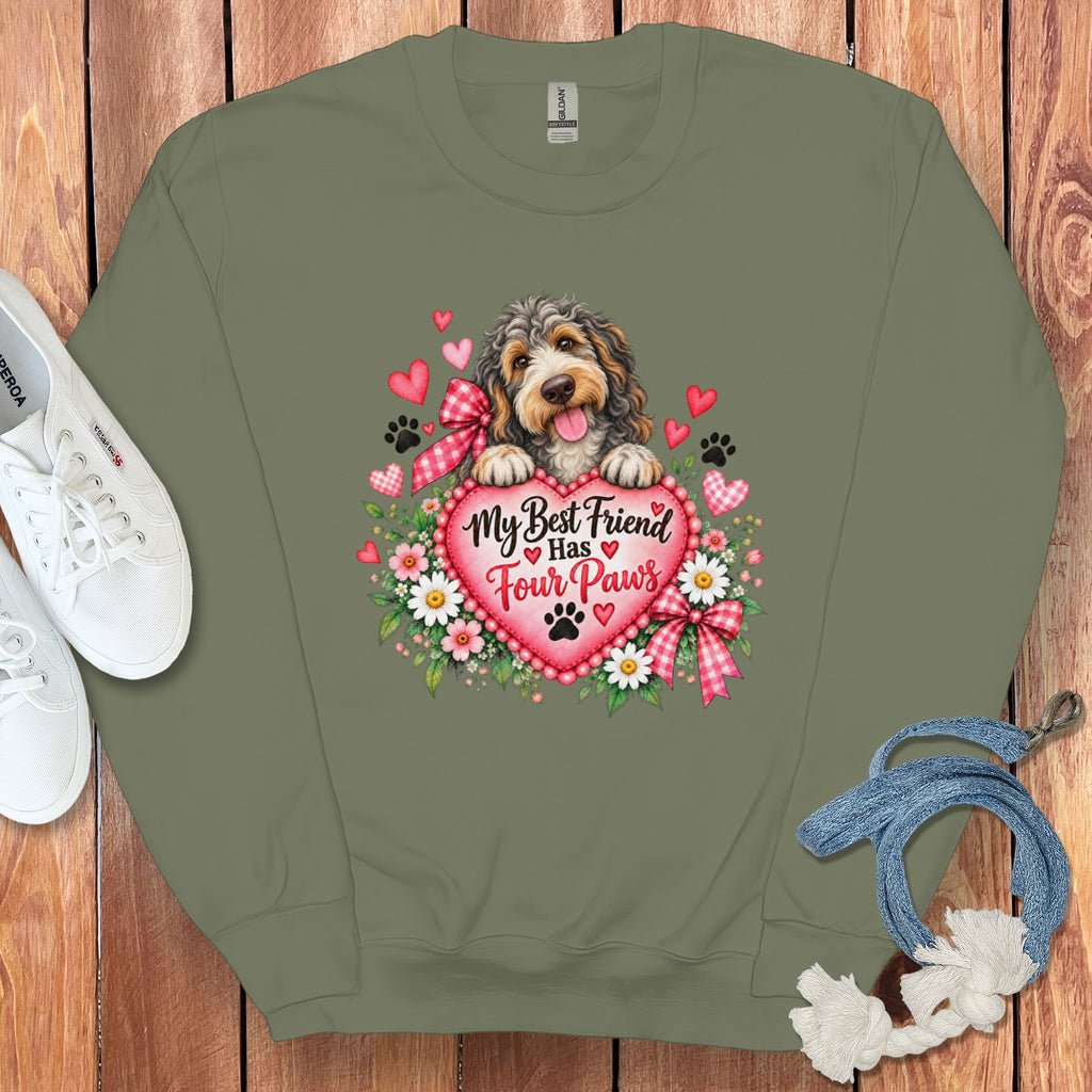 An olive green crewneck sweatshirt featuring a graphic of a dog, hearts, flowers, and the text My Best Friend Has Four Paws.