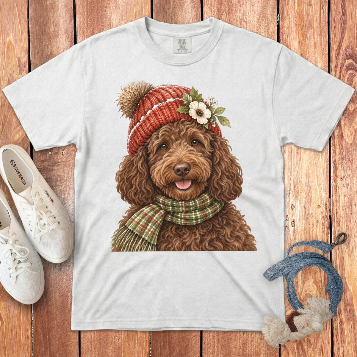 White t-shirt with watercolor illustration of a brown doodle dog wearing a red knit hat and scarf.