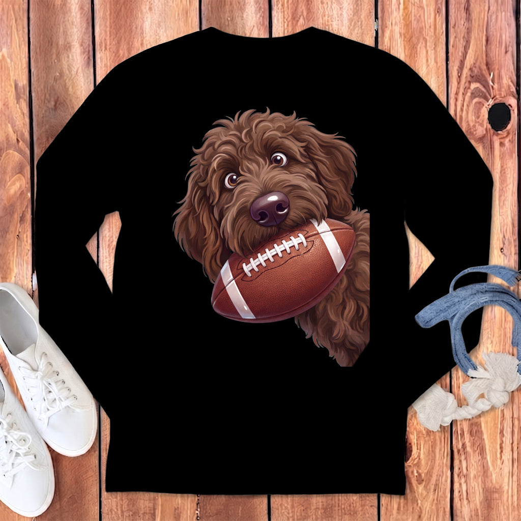 Brown doodle dog holding a football on a black shirt.