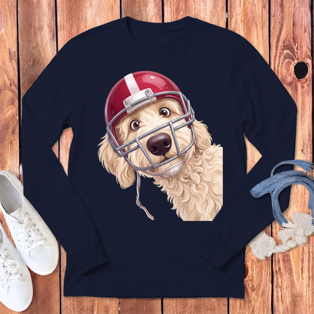 Golden doodle dog wearing a red and white football helmet on a navy t-shirt.