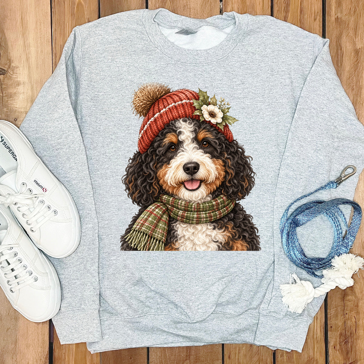 Bernese Mountain Dog wearing winter hat and scarf, on a grey sweatshirt.